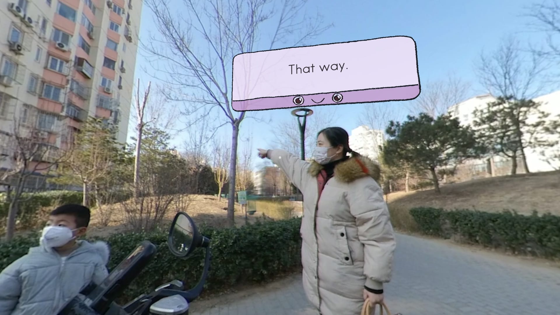 A screenshot from OUT FOR DELIVERY, Heart Street collective's documentary game. The shot features a person in a mask with long hair in a ponytail pointing to somewhere behind them. A text box characterized with a cartoon smiling face reads "That way." There is a young person with short hair and a mask to her right and near them is what looks like part of an electric bike. They appear to be in a park.